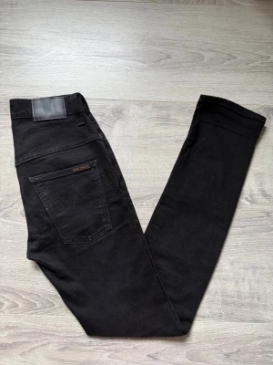 Svarta  jeans från Nudie Jeans - Säljer ett par väldigt snygga svarta  jeans från Nudie i storlek W29 L32. Jeansen är i väldigt fint skick utan några defekter. Vid fundering är det bara att hojta till !