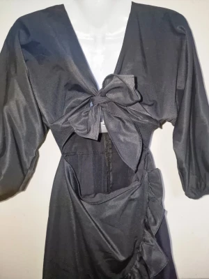 Svart omlottklänning med rosett - Svart klänning med knytning framtill och puffiga ärmar.