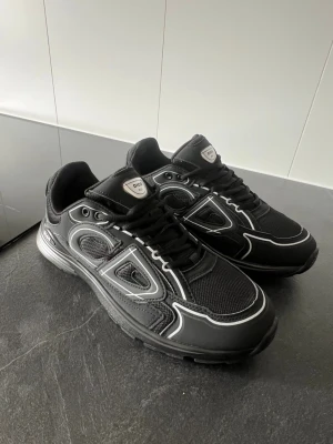 Dior b30  - Snygga svarta Dior sneakers med vita kontrastdetaljer och meshpaneler. Skorna har en chunky sula och tydliga Dior-loggor på sidan och plösen. Helt nya, aldrig använd. Storlek 42 kan passa 43