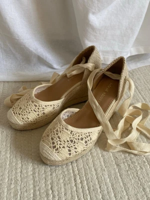 Sandaletter kilklack - Söta sandaletter med kilklack i en beige/cremevit färg. Sula undertill cirka 22cm, kilklack: cirka 8cm. Aldrig använda då de va förstora för mig, fick de i present