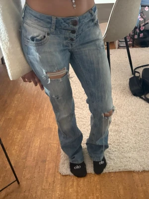 Ljusblå slitna jeans med knappar - Är 160, 32/34 midja , low waist