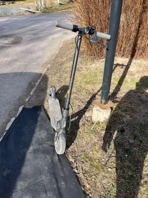 Svart elsparkcykel med grå detaljer - Säljer en svart elsparkcykel med grå detaljer och robusta hjul. Styret har en enkel design och det finns reflexer på bakhjulet. Perfekt för att ta sig fram snabbt i stan eller till skolan. Laddningsuttag finns på sidan av fotplattan.