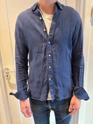 Marinblå linneskjorta John Henric  - Marinblå linneskjorta 100% linne från John Henric. Passformen är slim fit. Använd fåtal gånger.
