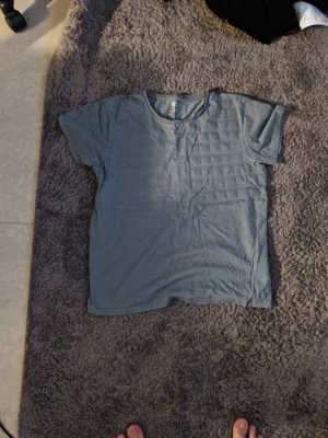 Blå basic t-shirt från H&M - En enkel blå t-shirt från H&M med rund hals och korta ärmar. Tillverkad i mjuk bomull och har en avslappnad passform. Perfekt till jeans eller shorts för en clean och enkel look.