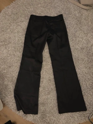 Svarta utsvängda kostymbyxor - Säljer ett par supercoola glansiga kostymbyxor💕