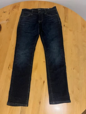 Mörkblå raka jeans från Jack & Jones - Snygga mörkblå jeans från Jack & Jones  med rak passform och klassisk femficksdesign. Jeansen har kontrastsömmar och en läderpatch bak i midjan. Tillverkade i slitstark denim som ger en cool och tidlös look.