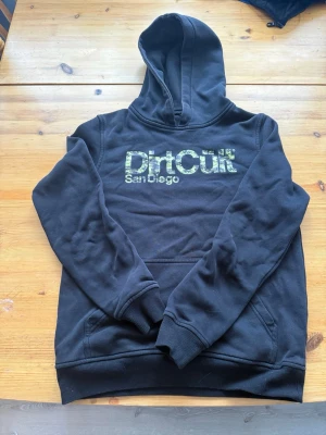 Dirticult Hoodie Storelk 158/164 - Svart Dirtcult Hoodie med militär tryck i storlek 158/164 mycket fint skick lite slitage på trycket men inget man märker 