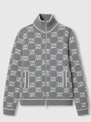 Grå zip-kofta från Gucci made in Italy - Grå kofta med hel dragkedja från Gucci, tillverkad i Italien. Stickad i mjukt material med vit GG-logomönster över hela plagget. Hög krage och ribbade muddar, samt vita detaljer vid fickorna. Perfekt för dig som vill ha något exklusivt och trendigt.