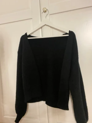 Svart stickad kofta - Mysig svart stickad kofta med lång ärm och avslappnad passform. Perfekt att slänga över en topp för en enkel och stilren look