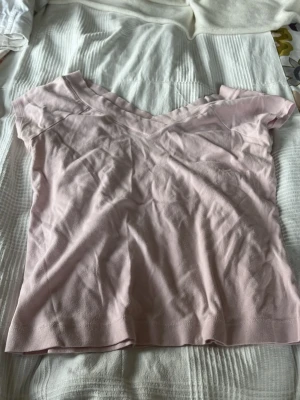 Ljusrosa v-ringad topp från Lindex - Söt ljusrosa topp från Lindex med v-ringning och korta ärmar. Tillverkad i mjuk bomull som känns skön mot huden. Perfekt att matcha med jeans eller kjol för en enkel och fräsch look. Storlek L