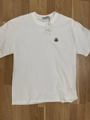 Vit t-shirt från Moncler - Vit moncler t-shirt storlek M helt oanvänd. Perfekt nu till sommaren. Skriv om du undrar något över tröjan. Priset kan diskuteras.