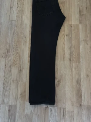 Svarta raka jeans - Säljer ett par svarta jeans med rak passform och klassisk femficksdesign. Jeansen har en enkel look utan slitningar eller dekorationer, perfekta till en avslappnad stil. Materialet känns som bomullsdenim med lite stretch.