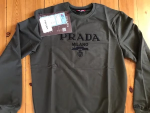 En tröja khaki från Prada - Säljer en långärmad tröja,khaki från Prada med broderad PRADA MILANO-logga på bröstet, stilren design, perfekta för en trendig look.