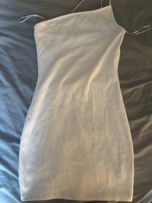 Vit ribbad oneshoulder klänning  - Säljer en vit ribbad kortklänning med oneshoulder-design och tunna axelband. Endast använd en gång✨
