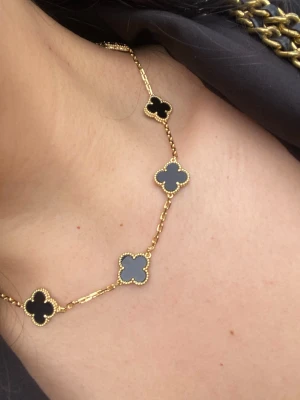 Guldpläterad med svarta klöverhängen, topp kvalitet - Snyggt halsband i guldton med fyra klöverformade hängen i svart . Kedjan är tunn och elegant, och varje hänge har en pärlad kant som ger extra detalj. Perfekt för dig som gillar stilrena accessoarer med en twist. Hypoallergenic 