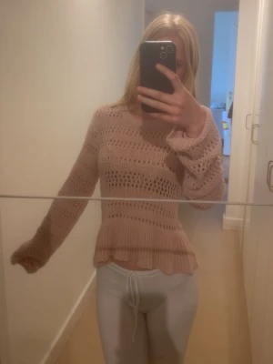 Rosa stickad volangtröja H&M - Det är strkl xxs men passar xs då jag har xs och den sitter perfekt. Änvänd en gång. Söt stickad tröja i ljusrosa från H&M med volangkant nedtill och hålmönster över hela plagget. Tröjan har rund halsringning och långa ärmar. Perfekt för lager på lager och ger en romantisk vibe till din outfit.