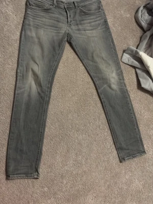 Grå slim fit jeans från Dondup - Snygga grå slim fit jeans från Dondup med slitna detaljer och klassisk femficksmodell. Jeansen har en tvättad look och smal passform som ger en modern vibe. Perfekta för dig som gillar stilrena och trendiga jeans.