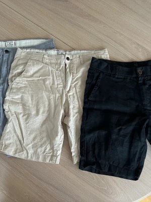 Tre par shorts  - Säljer alla tre tillsammans! Snygga shorts i linne-imitation! De beiga och ljusblå är ifrån Jack & Jones och de svarta är ifrån NDL. De alla är lika i passform. 