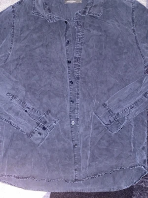 Mörkblå skjorta från Dressmann XL - Säljer en mörkblå skjorta från Dressmann i storlek XL. Skjortan har klassisk krage, långa ärmar och knappar framtill. Tillverkad i mjuk bomull och passar perfekt till en avslappnad stil.