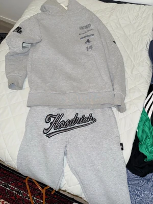 Grå Hoodrich loungewear set, väst, byxan blå allt(1000) - Säljer ett grått loungewear set från Hoodrich med hoodie och matchande byxor. Hoodien har tryck på bröstet och ärmen, medan byxorna har stor Hoodrich-logga framtill. Perfekt för chill dagar hemma eller streetwear vibes.
