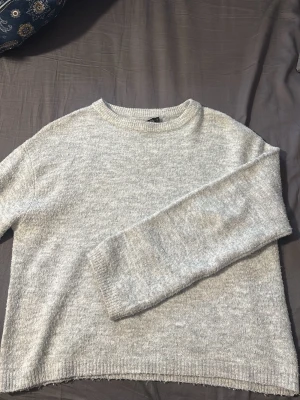 Ljusgrå stickad tröja från Lager 157 - Mysig ljusgrå stickad tröja med rund halsringning och ribbade muddar vid ärmslut och nederkant. Storlek S