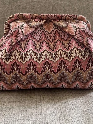 Mönstrad kuvertväska clutch - Unik kuvertväska med retroinspirerat mönster i rosa, vinrött och beige. Väskan har en mjuk, vadderad form och är tillverkad i ett tyg som liknar sammet eller gobeläng. Perfekt accessoar för dig som gillar vintage och statement-plagg i missoni zick Zack mönster Beck söndergaard 