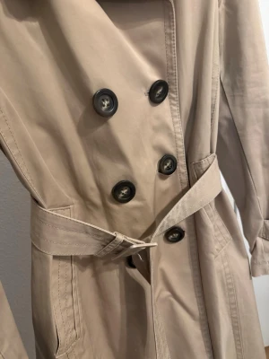 Beige trench coat from Massimo Dutti - Säljer min fine Massimo Dutti trenchcoat då den inte kommer till usvändning. Kappan är även kemtvättad och ej usvänd efter tvätten. Kappan kostar ny 2000 kr. Storleken på kappan är mer passad för en person med storlek S Jacketan även mestadels bomull. jackan har små skavanker på sig därav pris. 