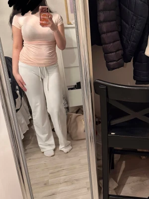 Ljusrosa tight topp med kort ärm - Säljer en ljusrosa tight topp med kort ärm och rund hals. Toppen har en enkel och clean design som sitter figurnära och är perfekt att styla med både jeans och mjukisbyxor. Materialet känns mjukt och stretchigt.