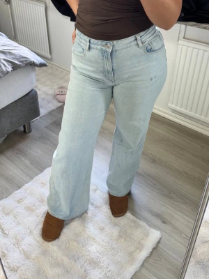Ljusblåa raka jeans med hög midja - Säljer ett par ljusblå jeans från Hm med rak passform och hög midja. Jeansen har klassisk femficksdesign och är tillverkade i ett mjukt denimtyg. Perfekta för en avslappnad och trendig look.