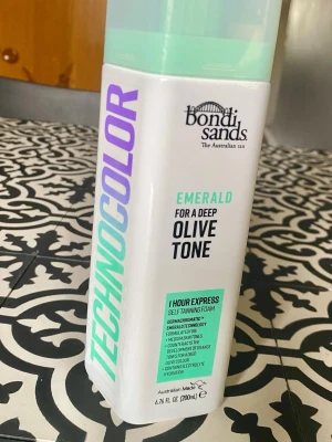 Bondi Sands Technocolor Emerald Brun utan sol - Bondi Sands Technocolor Emerald är en 1-timmes express brun utan sol-mousse för djup olivton. Flaskan är vit med mintgrönt och lila tryck, och rymmer 200 ml. Produkten är en self-tanning foam med återfuktande egenskaper och passar dig som vill ha en naturlig solbränna. Endast öppnad.