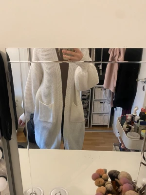 Vit lång stickad kofta med fickor - Mysig lång vit stickad kofta. Oversized passform och öppen framtill utan knappar eller dragkedja. Använd endast 3 gånger så är fortfarande i fint o nytt skick.