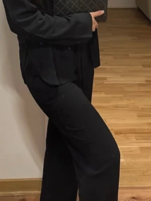 Nelly Linnebyxor - Säljer ett par svarta mjukisbyxor med avslappnad passform och dragsko i midjan. Byxorna har raka ben och är tillverkade i ett mjukt och bekvämt material som passar perfekt för chill dagar. Enkla att matcha med olika överdelar för en clean look.