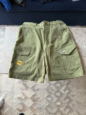 Olivgröna cargoshorts Corteiz  - långa cargo shorts från Corteiz. perfekta till sommaren och använda typ en gång