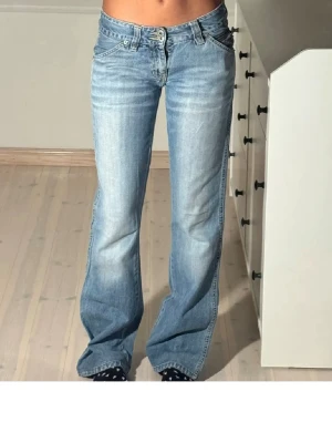 Ljusblå bootcut jeans - Säljer ett par ljusblå bootcut jeans med låg midja. Jeansen har ett litet hål som syns på en av bilderna men inget som märks när man har på dom. Perfekta till sneakers eller boots för en avslappnad stil. 