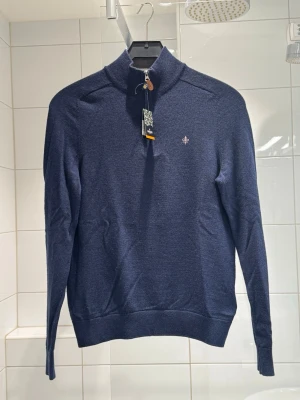 Mörkblå halvzip-tröja från Morris - Snygg mörkblå stickad tröja från Morris med halvzip och ståkrage. Tröjan har diskret logga broderad på bröstet och ribbade muddar vid ärmslut och nederkant. Perfekt för en stilren och avslappnad look. Tröjan är inprincip ny och är i nytt skick, Storlek bär S, nypris på denna tröjan är runt 1800kr, mitt pris 800kr, tveka inte att höra av er vid frågor eller funderingar😊