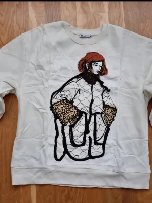 Vit sweatshirt med konstnärligt tryck - Vit sweatshirt från Cheap Monday med ett stort konstnärligt tryck framtill som föreställer en person i rock med detaljer i svart, beige och rött. Rund hals och långa ärmar. Perfekt för dig som gillar unika statement-plagg.