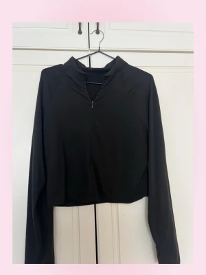 Svart croppad långärmad topp - 💗Svart croppad topp med lång ärm och hög krage. Toppen har en diskret half zip-dragkedja framtill kan dras ner ganska långt mens syns inte på bilden så bra och är tillverkad i ett mjukt, stretchigt material som ger en slim passform. Perfekt för en trendig och sportig look. 💕