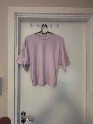 Ljuslila oversized t-shirt - En enkel och stilren ljuslila t-shirt med oversized passform och korta ärmar. Tillverkad i mjuk bomull som känns skön mot huden. Perfekt för en avslappnad look och lätt att matcha med jeans eller shorts.