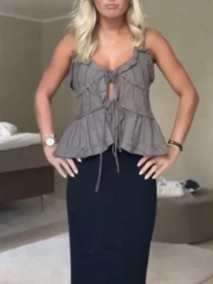 Zara topp  - Säljer en grå blus med omlott-design och snörning framtill. Blusen har volangdetaljer och tunna axelband, vilket ger en feminin och trendig look. Perfekt att matcha med både jeans och kjol. Materialet känns lätt och luftigt.