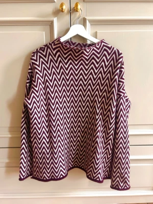 Stickad tröja med zigzag-mönster - Säljer denna fina stickade tröja från Dagmar med snyggt zigzag-mönster i vinrött och vitt. Tröjan har rund halsringning, långa ärmar och avslappnad passform. 