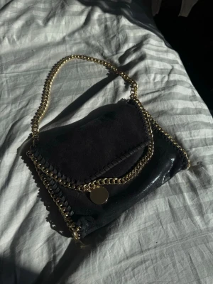 Svart Stella McCartney handväska guld - Säljer pga att det inte är min stil längre. Mycket utrymme och lätt att ha med sig 