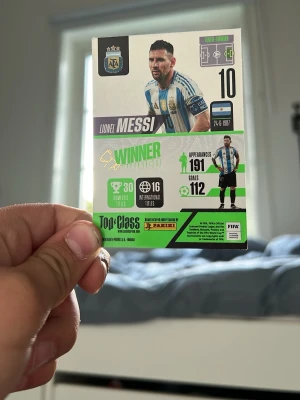 Panini Winner fotbollskort Messi - Säljer ett Panini Winner fotbollskort med Lionel Messi från Argentina. Kortet har svart, vitt, grönt och blått tryck med statistik och grafik. Materialet är glansig kartong och motivet visar Messi i landslagströjan. Perfekt för samlare av sportkort.
