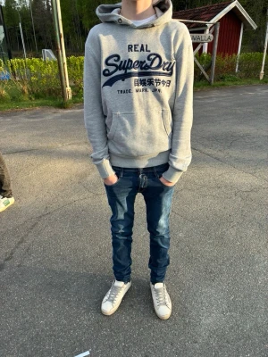 Grå Superdry hoodie med tryck - Säljer en grå hoodie från superdry, modellen är 182, skriv vid funderingar. Pris kan sänkas vid snabb affär