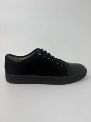 Svarta Lanvin sneakers med lackad tå - Stilrena svarta sneakers med ovandel i mocka och snygg lackad tådel. Skorna har svarta skosnören och en klassisk låg siluett. Perfekta för dig som gillar en clean look med en twist. Passar till både jeans och dressade outfits.