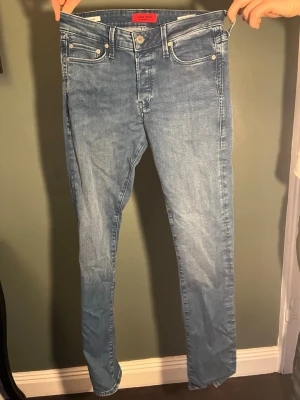 Ljusblå slim fit jeans från Jack & Jones - Säljer ett par ljusblå skinny jeans från Jack & Jones med klassisk femficksdesign och normalhög midja. Jeansen har en snygg tvätt och är tillverkade i stretchigt denim för extra komfort. Perfekta för en avslappnad och trendig look.