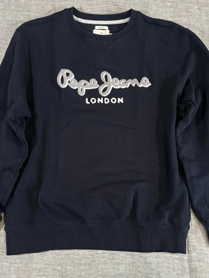 Pepe Jeans Lamont Crewneck Teddy Spellout XL Relaxed Fit - Pepe Jeans Lamont Crewneck with large chenille/teddy spellout logo across the chest. Clean relaxed fit with heavyweight feel and soft interior. Easy everyday Y2K/streetwear piece in a versatile dark navy colorway.  Size XL (fits relaxed)  Measurements: P2P: 62.5 cm S2S: 50 cm Length: 67 cm  Good used condition with normal wear. No major flaws noticed.  Please compare measurements with a sweatshirt you own for best fit. 