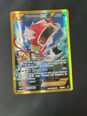 Pokémonkort Gyarados EX  - Säljer ett Gyarados EX Pokémonkort med holografisk yta. Kortet har färgstark design med Gyarados i rött och blått, guldkant och detaljer i silver. Engelskspråkig text och klassisk Pokémon-baksida. Perfekt för samlare eller Pokémonfans.