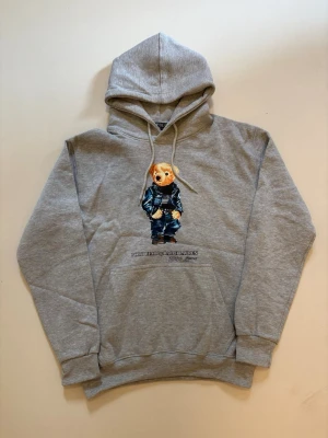 Grå Ralph Lauren Polo bear hoodie - Grå Ralph Lauren Polo bear hoodie // 10/10 skick helt oanvänd // Storlek M // längd 64cm  axelbredd 49cm armlängd 59cm // skriv vid minsta fråga eller fundering🤝
