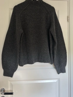 Mörkgrå stickad tröja med polokrage - Mysig mörkgrå stickad tröja med hög polokrage och breda, långa ärmar. Tröjan har en rak passform och är ribbstickad i ett tjockare material, perfekt för kyliga dagar. Enkel och stilren design som passar till det mesta💞kontakta vid fler frågor💞