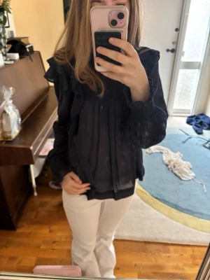 Mörkblå blus med volanger och smock neo nior  - Snygg mörkblå blus med volanger längs axlar och bröst, samt smockad detalj upptill. Blusen har lång ärm med spetsinslag. Tröjan ör från neo nior och säljs därför för lite dyrare pris men jag har ändå sänkt priset💘😊 strorlek 34 och i superbra skick🫶